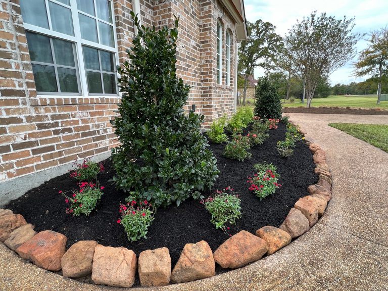 moss rock with trees, plants, mulch, gravel concrete landscape