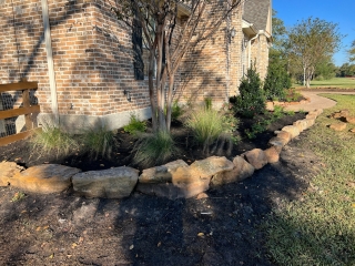 moss rock with pink muhly grass and crape myrtle and mulch